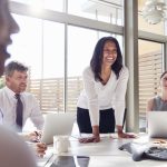 Smiling female manager listening to colleagues at a meeting