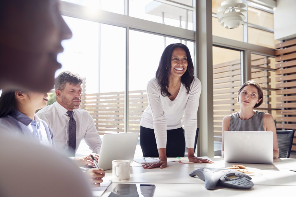 Smiling female manager listening to colleagues at a meeting
